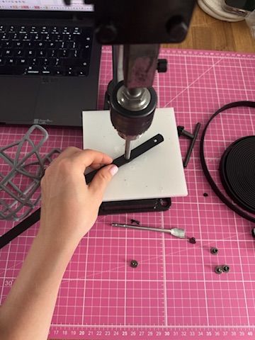 Strap being drilled by hand at a workbench